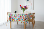 Folkstar Łowicz white folk tablecloth on a wooden dining table with black mug and fresh flowers