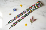 Folkstar Łowicz rooster folk shoelaces laid flat on marble surface with dried wildflowers