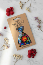 Folkstar Folk Zapach Leśna Malina freshener on marble surface with dried wildflowers and fresh red berries
