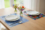 Folkstar Kujawy blue and Łowicz black placemats set on a wooden dining table with white plates cutlery and wildflowers