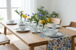 Folkstar Kashubian folk table runner styled on a natural wooden dining table with white ceramic plates and fresh flowers